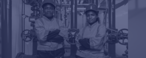 En man och kvinna i arbetskläder och skyddshjälmar står på var sin sida om en pumpstation.